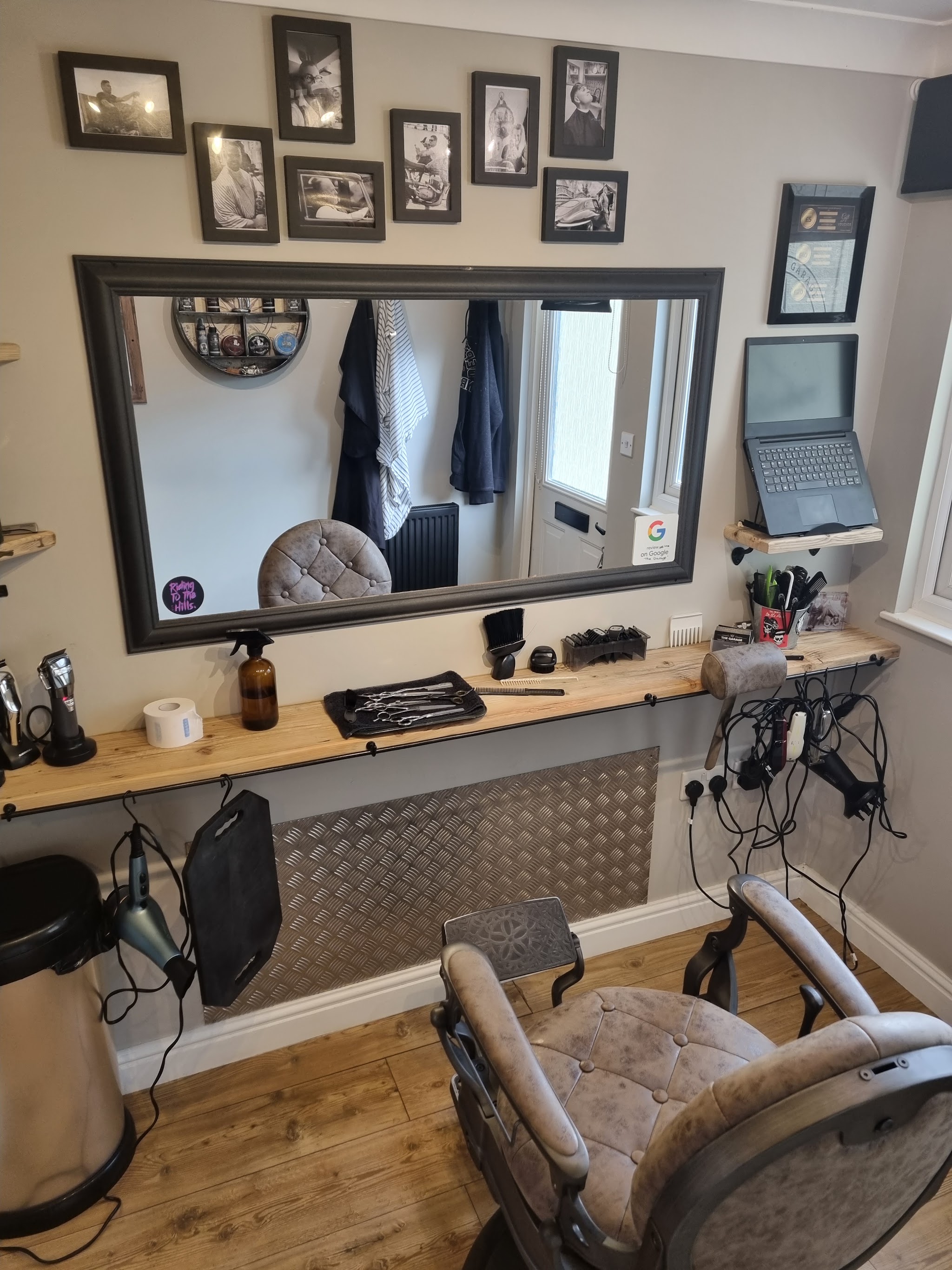 Tracey's vintage barber chair in front of the mirror and a wall of framed black and white photos
