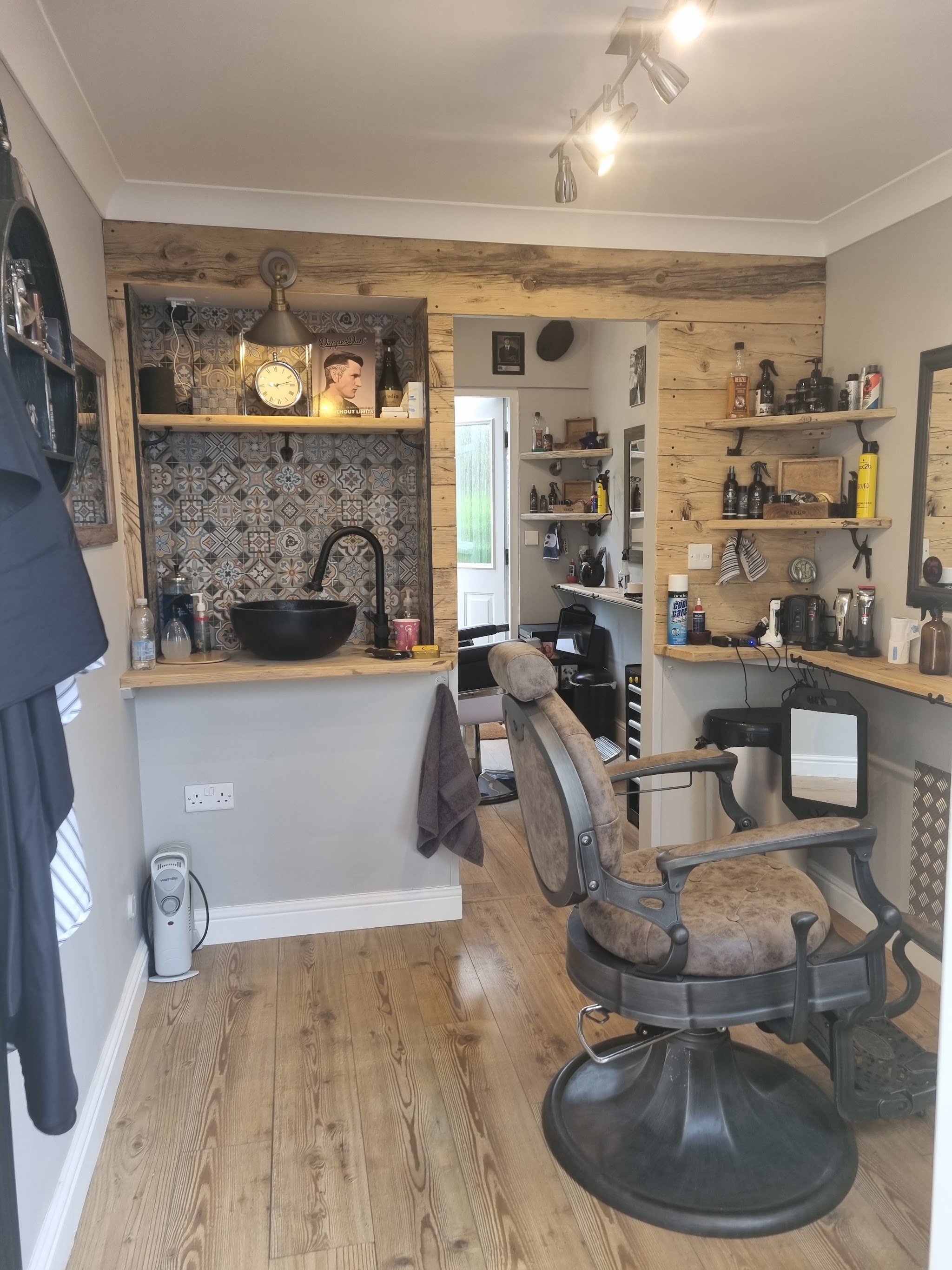 The shop: wood-clad wall, tiled wash basin and a vintage barber chair under track lights